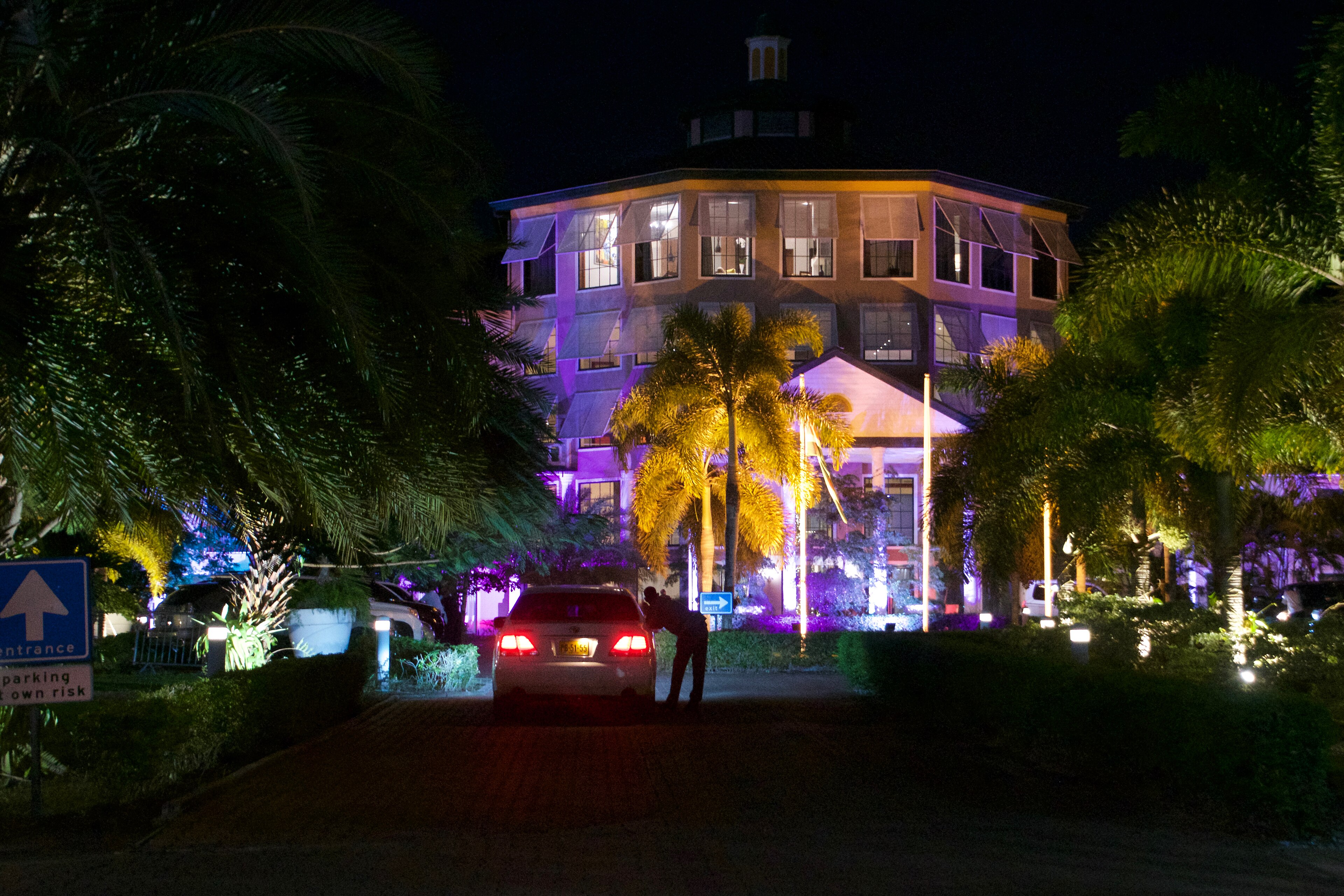 A lit colonial building among palm trees in Paramaribo in the evening.